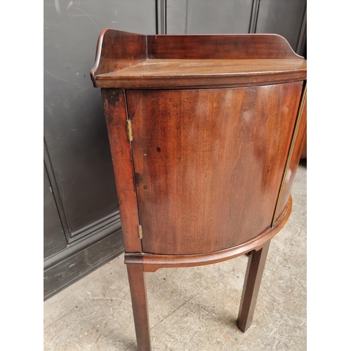 1051 - An antique mahogany bowfront corner washstand, 66.5cm wide.