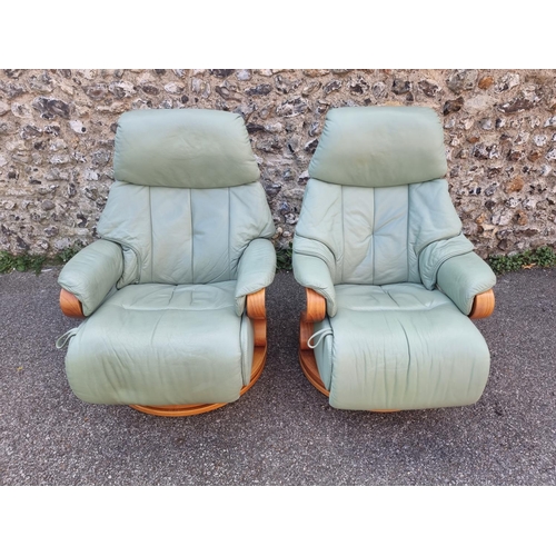 1068 - A pair of Himolla 'Chester' pale green leather reclining and swivel easy chairs.