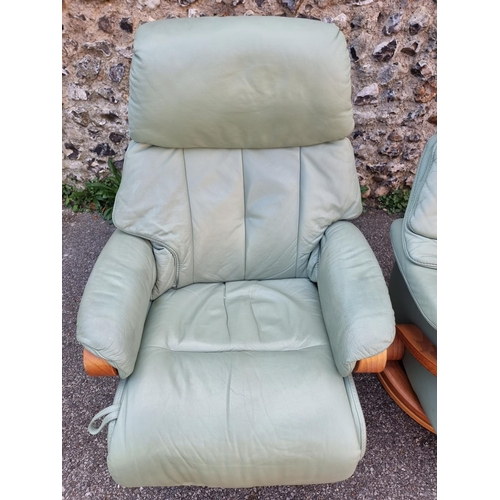 1068 - A pair of Himolla 'Chester' pale green leather reclining and swivel easy chairs.