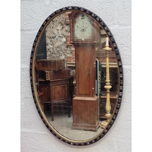 1089 - A large Irish style oval wall mirror, bearing label, 87 x 61.5cm.