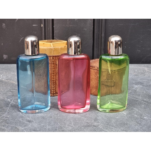 1429 - A vintage leather cased set of three coloured glass scent bottles, 12.5cm high.... 