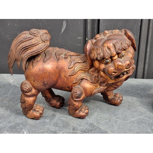 1523 - A Chinese carved giltwood lion dog, 23.5cm long; together with another Chinese carved giltwood figur... 