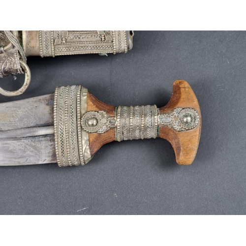 512 - A 20th century Omani seven ring metal clad jambiya, with wooden hilt, having 17cm blade.... 