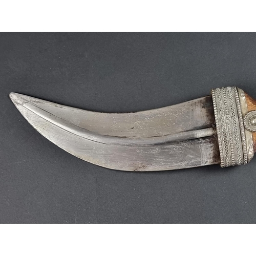 512 - A 20th century Omani seven ring metal clad jambiya, with wooden hilt, having 17cm blade.... 