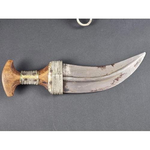 512 - A 20th century Omani seven ring metal clad jambiya, with wooden hilt, having 17cm blade.... 