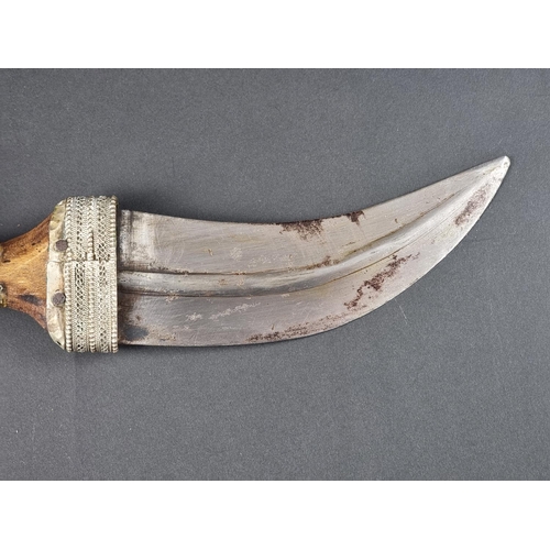 512 - A 20th century Omani seven ring metal clad jambiya, with wooden hilt, having 17cm blade.... 