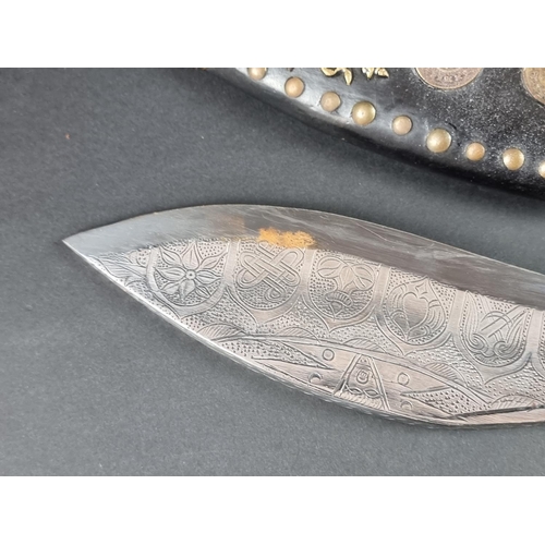 521 - A kukri and scabbard, with 22cm chased blade; together with another similar example. (2)... 