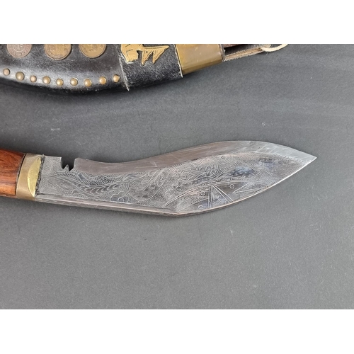 521 - A kukri and scabbard, with 22cm chased blade; together with another similar example. (2)... 