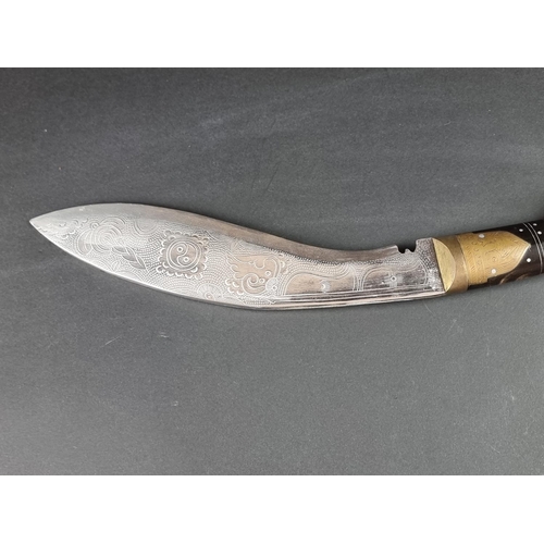 521 - A kukri and scabbard, with 22cm chased blade; together with another similar example. (2)... 