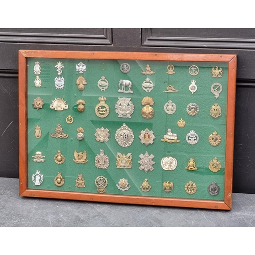 778 - A framed display of fifty-four military cap badges, 48 x 70cm