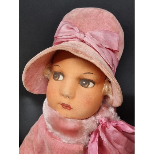 86 - Doll: a vintage cloth doll in pink fur trimmed coat and hat; together with an old green straw filled... 