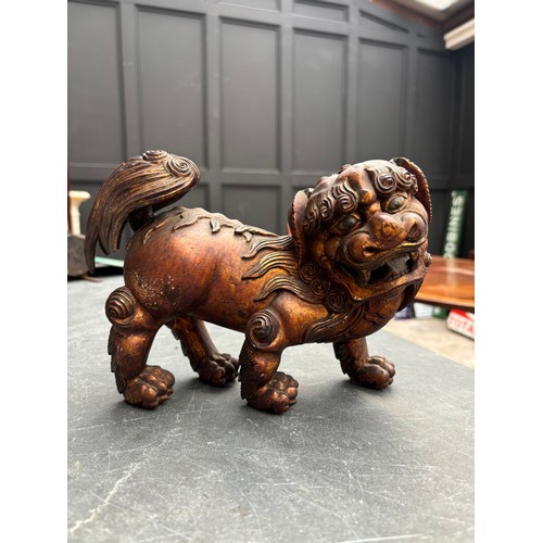 1523 - A Chinese carved giltwood lion dog, 23.5cm long; together with another Chinese carved giltwood figur... 