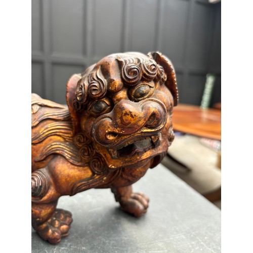 1523 - A Chinese carved giltwood lion dog, 23.5cm long; together with another Chinese carved giltwood figur... 