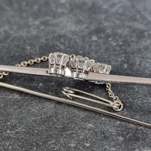 230 - A white metal diamond three stone bar brooch, set graduated brilliant cut stones, totalling approxim... 