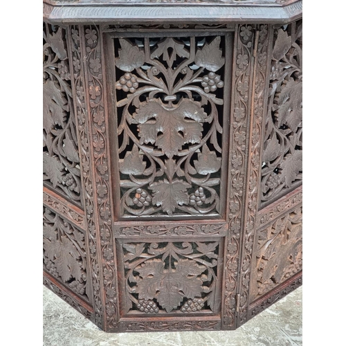 1028 - An Eastern carved and pierced hardwood octagonal folding table, 60cm wide.