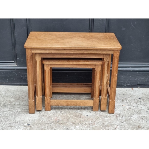 1056 - A nest of three Robert 'Mouseman' Thompson oak tables, largest 61cm wide.