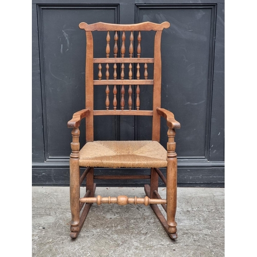 1067 - A Victorian ash, fruitwood and rush seated spindle back rocking chair.