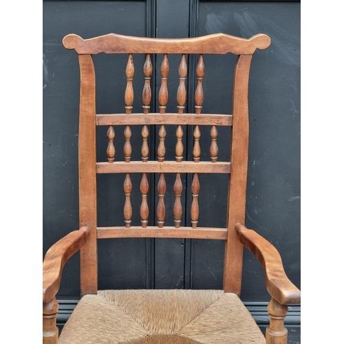 1067 - A Victorian ash, fruitwood and rush seated spindle back rocking chair.