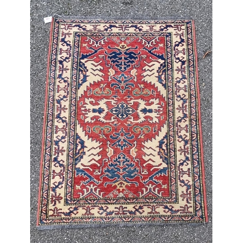 1129 - A Persian rug, having geometric design to central field, with geometric borders, on red and cream gr... 