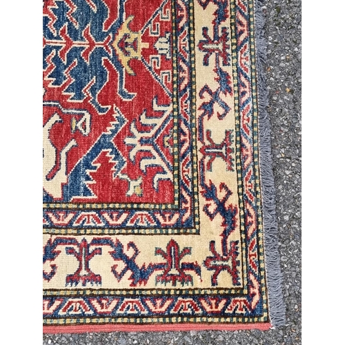 1129 - A Persian rug, having geometric design to central field, with geometric borders, on red and cream gr... 