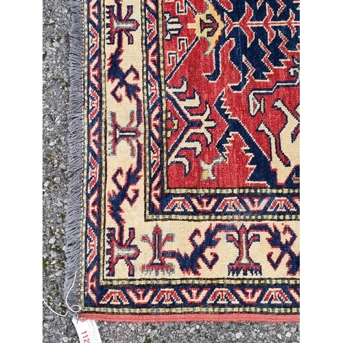 1129 - A Persian rug, having geometric design to central field, with geometric borders, on red and cream gr... 