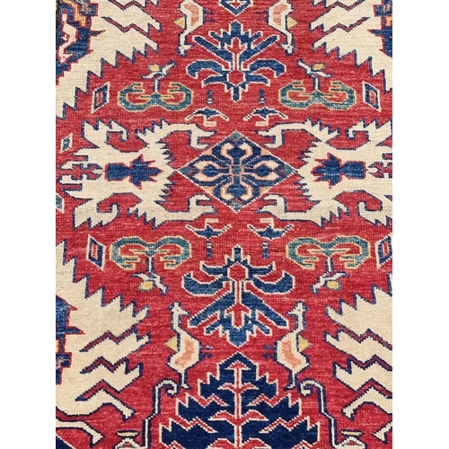 1129 - A Persian rug, having geometric design to central field, with geometric borders, on red and cream gr... 