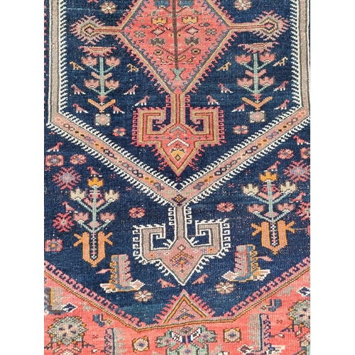 1132 - A Persian rug, central field decorated with diamond medallion and trees, with floral borders, 205 x ... 