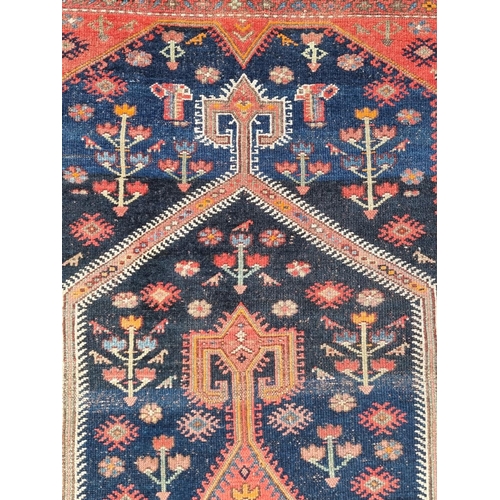 1132 - A Persian rug, central field decorated with diamond medallion and trees, with floral borders, 205 x ... 