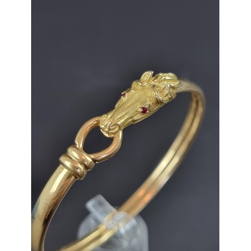 233 - A Gay Frères bangle, decorated stylised horse head with faceted ruby set eyes, having stamped maker'... 