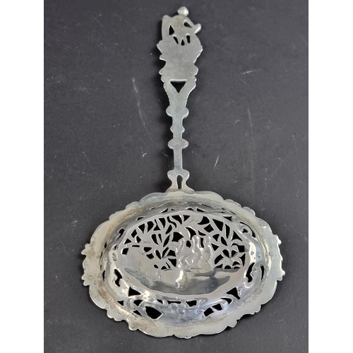 74 - A Continental metal sifter spoon, having figural terminal and decorative bowl.