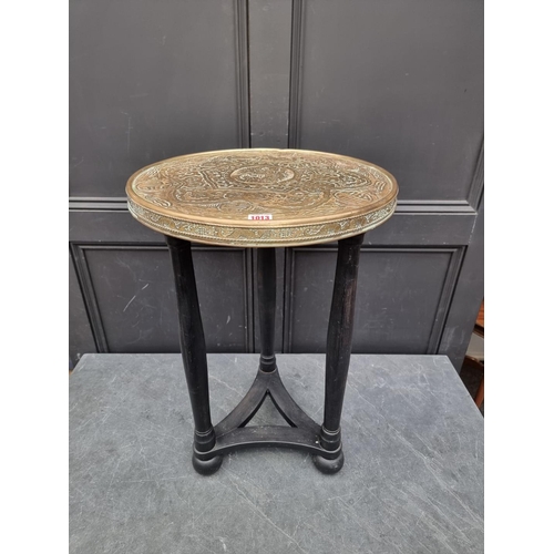 1013 - A brass and ebonized circular table, the top decorated with Chinese motifs, 46cm diameter.... 