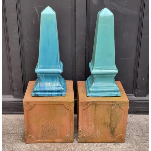 1772 - A pair of turquoise glazed stoneware obelisks, 68cm high, on terracotta stands, total height 108cm.... 