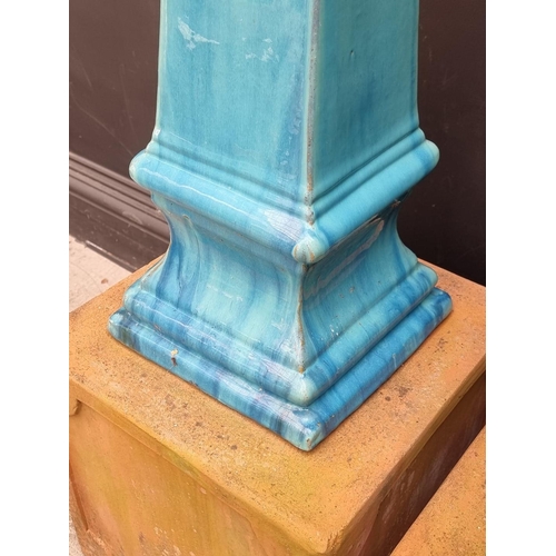 1772 - A pair of turquoise glazed stoneware obelisks, 68cm high, on terracotta stands, total height 108cm.... 