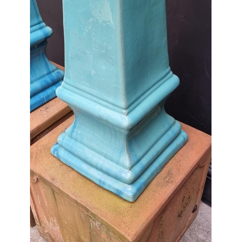 1772 - A pair of turquoise glazed stoneware obelisks, 68cm high, on terracotta stands, total height 108cm.... 