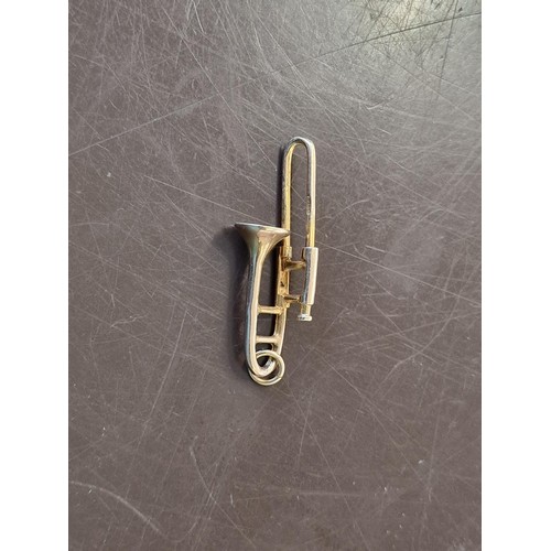 320A - A 9ct gold novelty trombone charm, 3.2cm long, 2.1g.