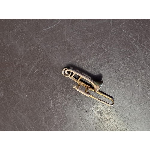 320A - A 9ct gold novelty trombone charm, 3.2cm long, 2.1g.