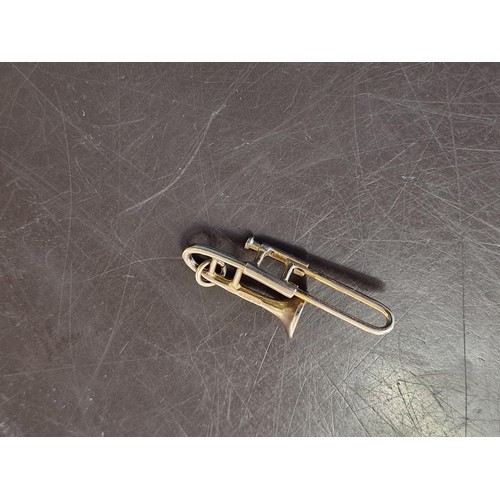 320A - A 9ct gold novelty trombone charm, 3.2cm long, 2.1g.