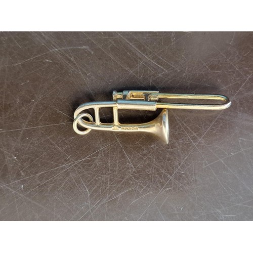 320A - A 9ct gold novelty trombone charm, 3.2cm long, 2.1g.