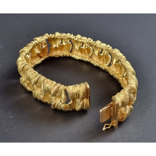 238 - A chunky yellow metal bracelet, designed as two rows of stylised leaves, stamped 'T 18k/0750 078', 1... 