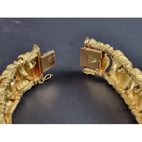 238 - A chunky yellow metal bracelet, designed as two rows of stylised leaves, stamped 'T 18k/0750 078', 1... 