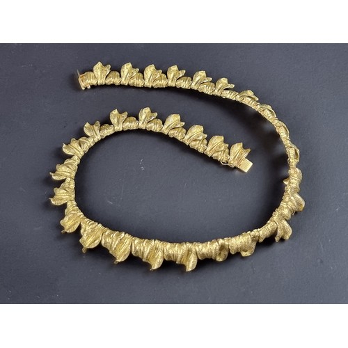 239 - A chunky yellow metal necklace, designed as a single row of overlapping leaves, stamped 'T 0750 AM39... 