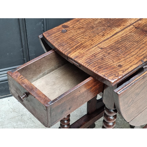 1058 - A late 17th century oak gateleg table, with lateral frieze drawer, 88cm wide.