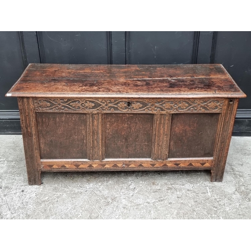 1067 - A late 17th century oak and inlaid panel coffer, with carved frieze, 131cm wide.... 