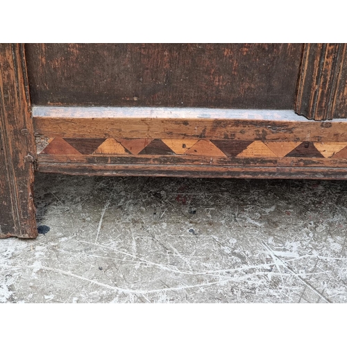 1067 - A late 17th century oak and inlaid panel coffer, with carved frieze, 131cm wide.... 