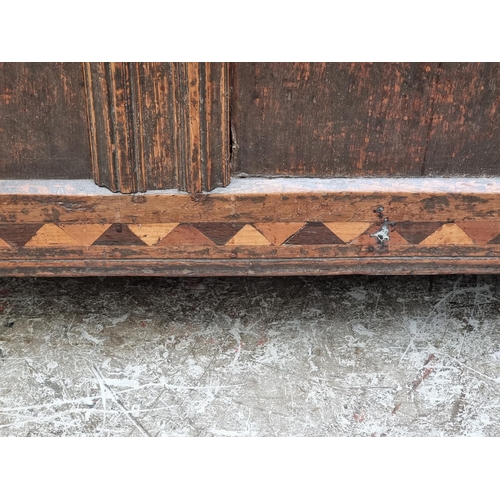 1067 - A late 17th century oak and inlaid panel coffer, with carved frieze, 131cm wide.... 