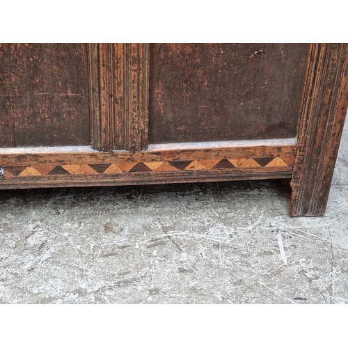 1067 - A late 17th century oak and inlaid panel coffer, with carved frieze, 131cm wide.... 