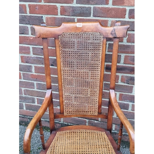 1080 - A 19th century fruitwood and cane open arm elbow chair. 