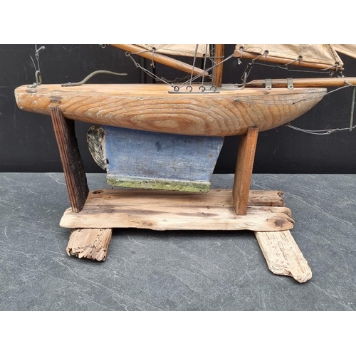 1526 - A small old pine pond yacht, the hull 48cm long, on conforming stand, total height 71cm.... 