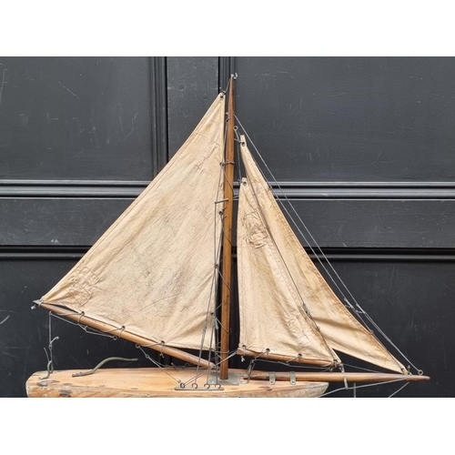 1526 - A small old pine pond yacht, the hull 48cm long, on conforming stand, total height 71cm.... 