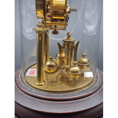 1093 - A brass anniversary timepiece, with glass dome, 32.5cm high.